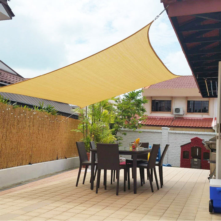Grijs vierkant schaduwdoek bevestigd aan muur en palen, voor maximale UV-bescherming op terras.