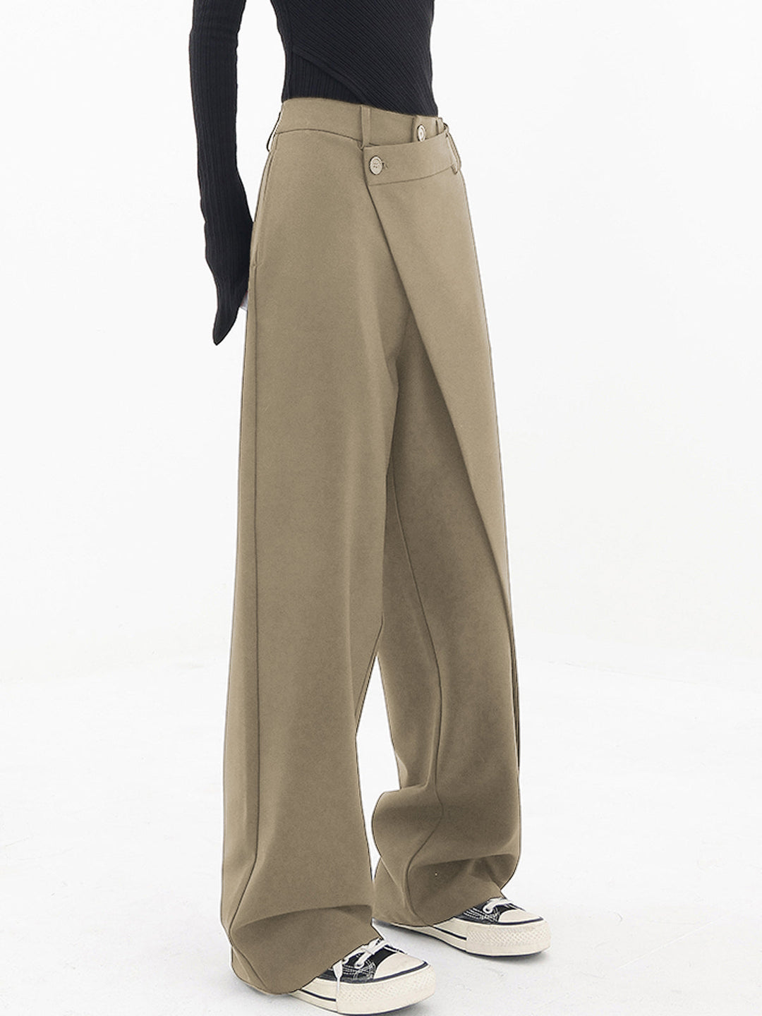 Vrouw draagt trendy Noa asymmetrische wijde broek met dubbele knoop, benadrukt de relaxte en stijlvolle pasvorm.