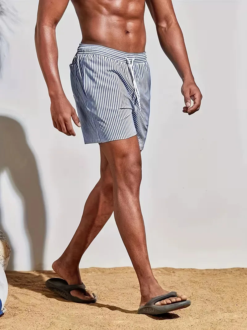 Detailopname van gestreepte heren zwemshorts in blauw en roze, toont stof en patroon. Essentiële zomer badmode.