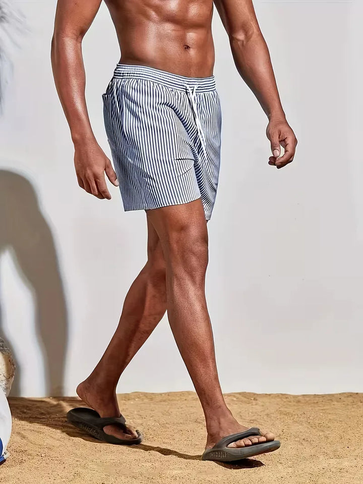 Detailopname van gestreepte heren zwemshorts in blauw en roze, toont stof en patroon. Essentiële zomer badmode.