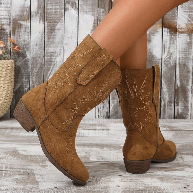 Gedetailleerde weergave van bruine leren dames cowboy enkellaarzen, comfortabel met karakteristieke middenhak.