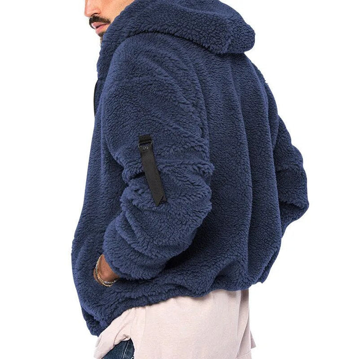 Model draagt comfortabel heren fleecevest met capuchon en rits, ideaal voor vrije tijd.