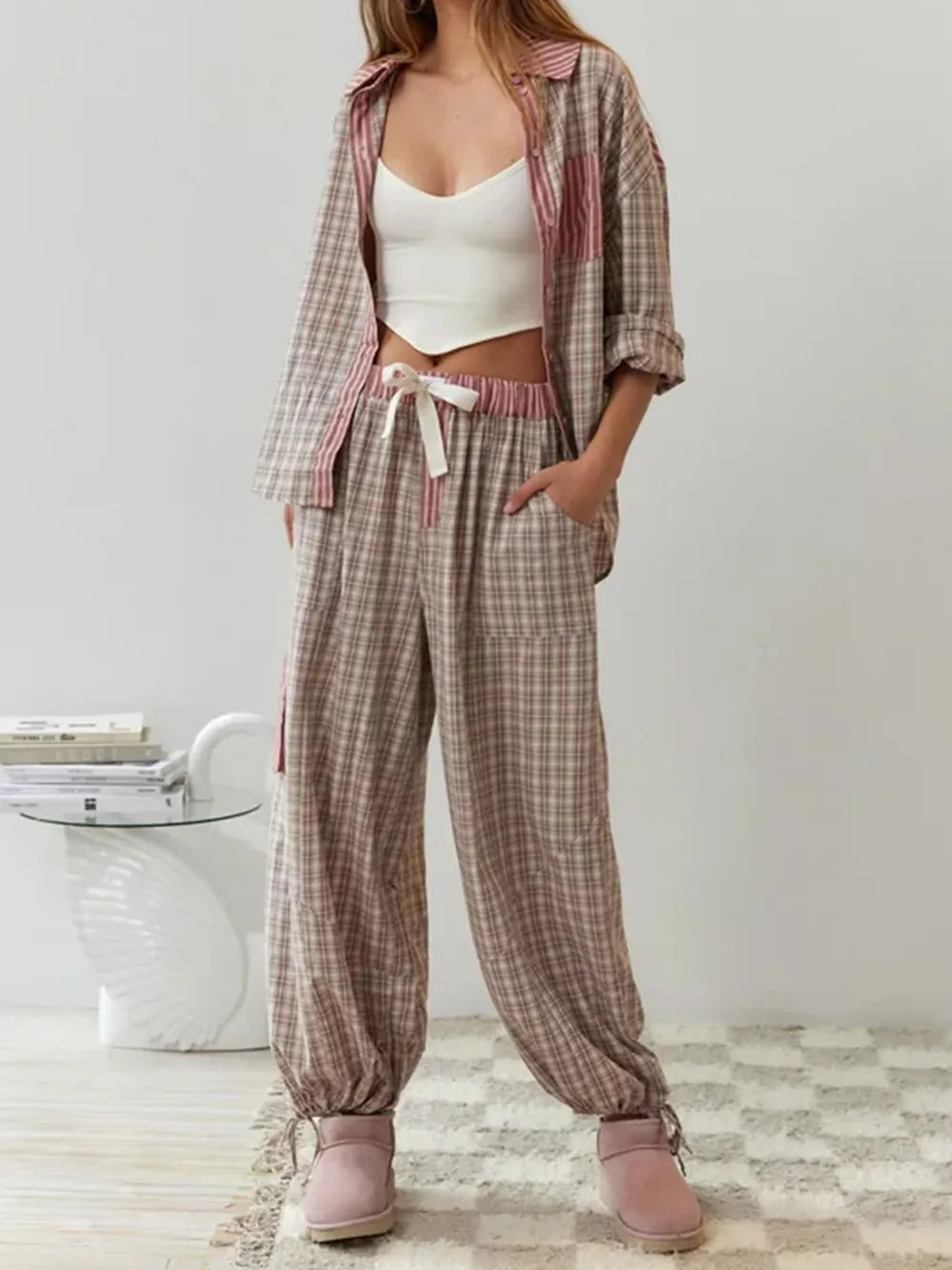 Vrouw ontspant met een boek, gekleed in comfortabele geruite damespyjamaset. Perfecte thuiskleding.