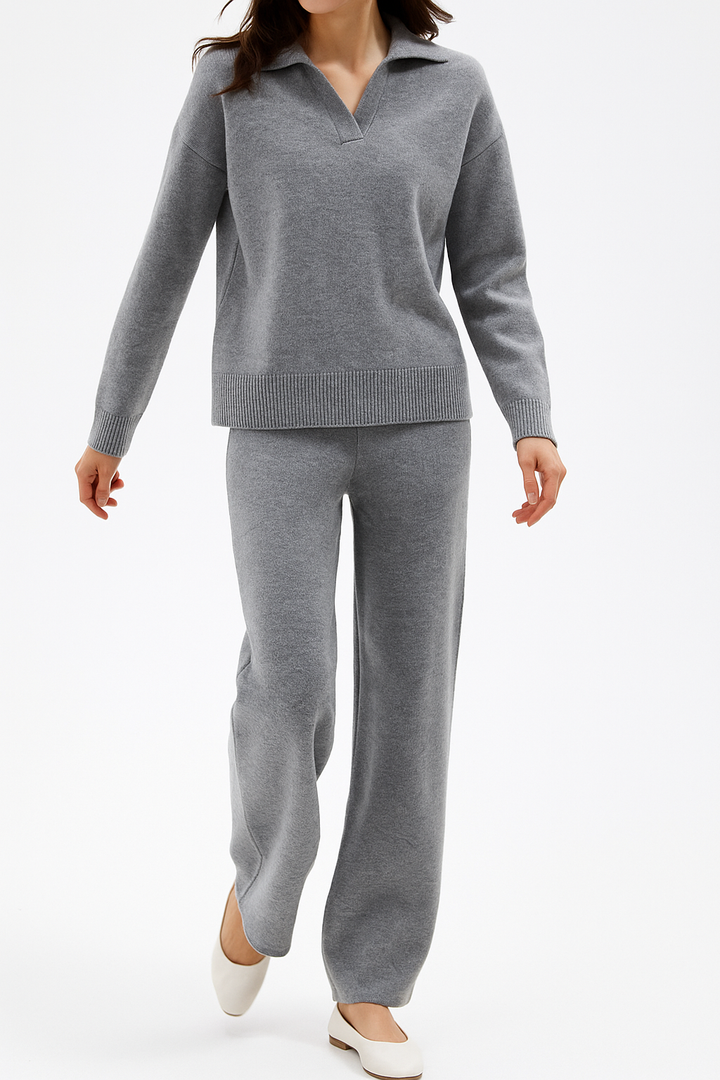 Vrouw ontspant in een modieuze dames loungewear set, bestaande uit een polotrui en een hoge taille broek.