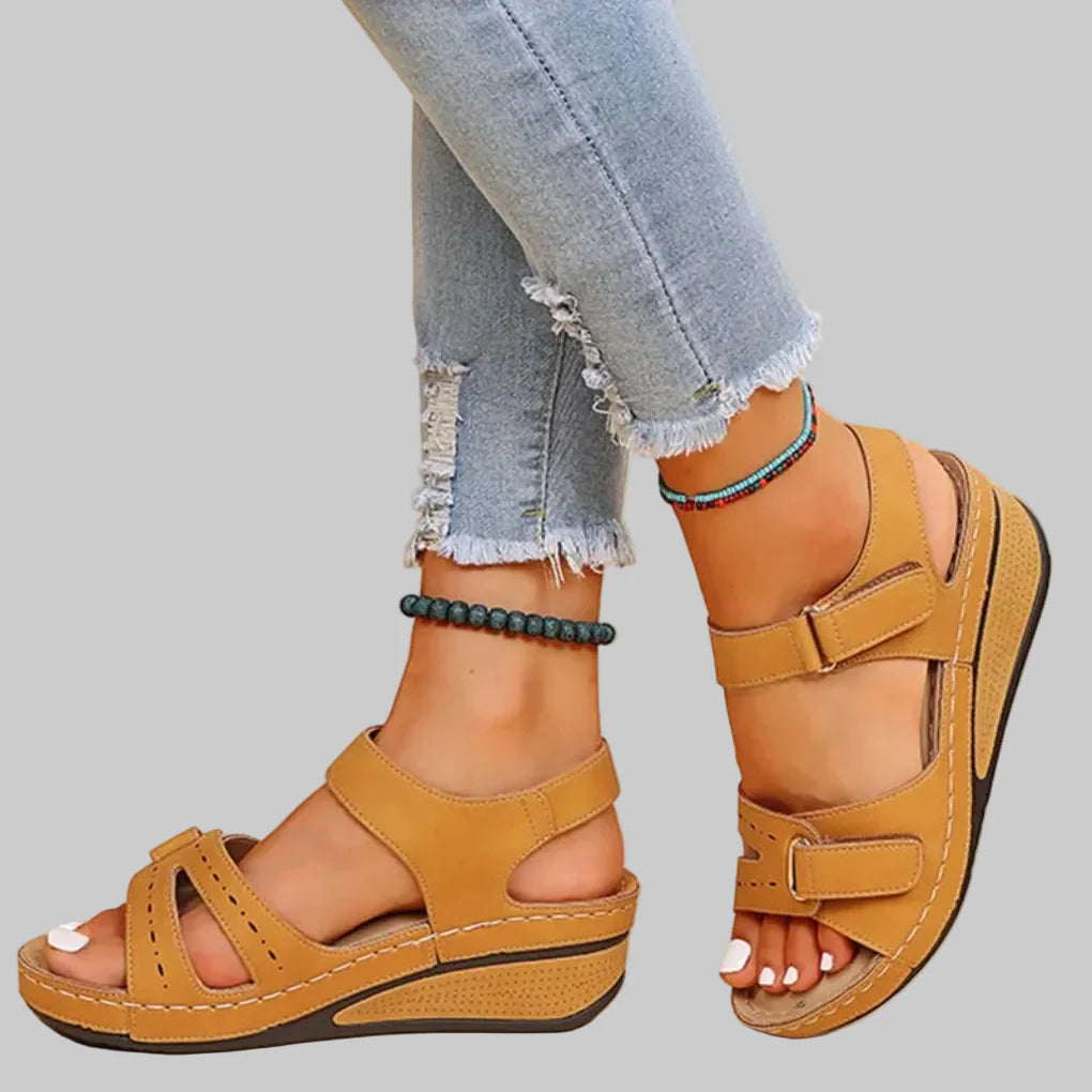 Dame draagt beige orthopedische sandalen, comfortabel en modieus, voor pijnverlichting tijdens het lopen.
