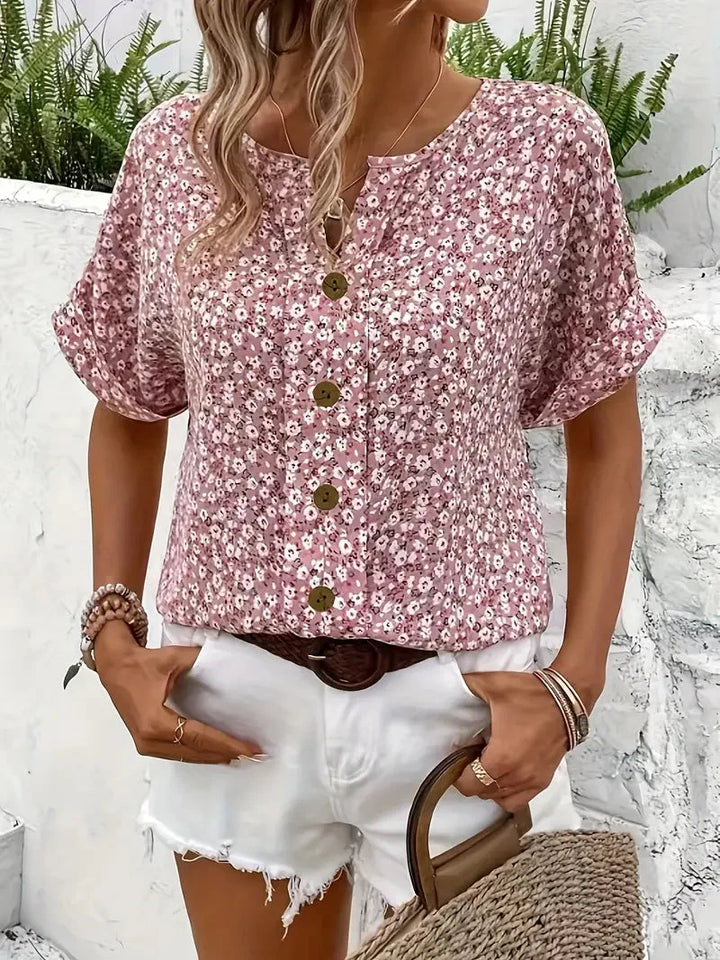 Roze dames blouse met vrolijke bloemenprint en korte mouwen. Comfortabele loose fit blouse met ronde hals.