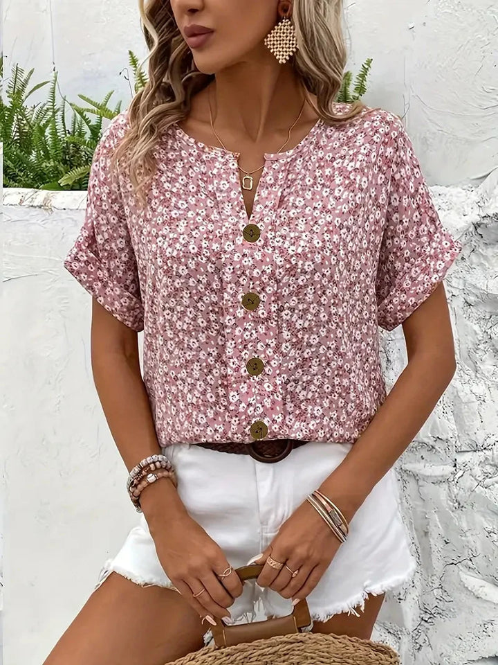 Modieuze dames blouse met bloemenprint, korte mouw en ronde hals. Zomerse roze loose fit blouse met knopen.