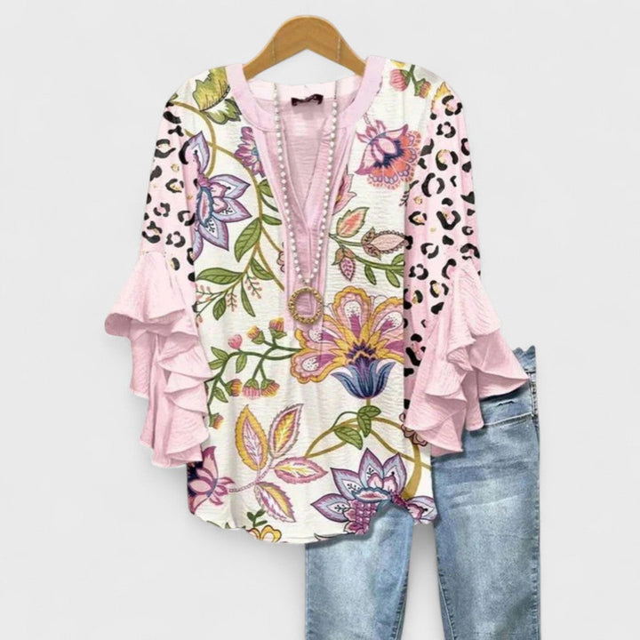 Model draagt een casual-chique damesblouse met V-hals en wapperende volantmouwen, perfecte mode.