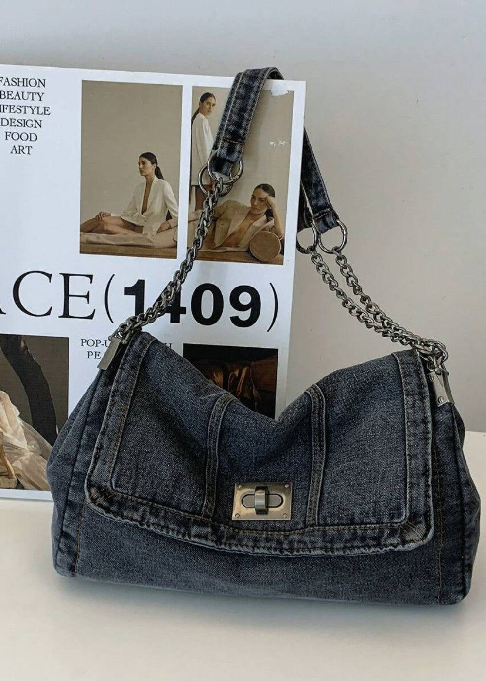 Trendy blauwe denim schoudertas voor dames, verfraaid met een chic metallic ketting.