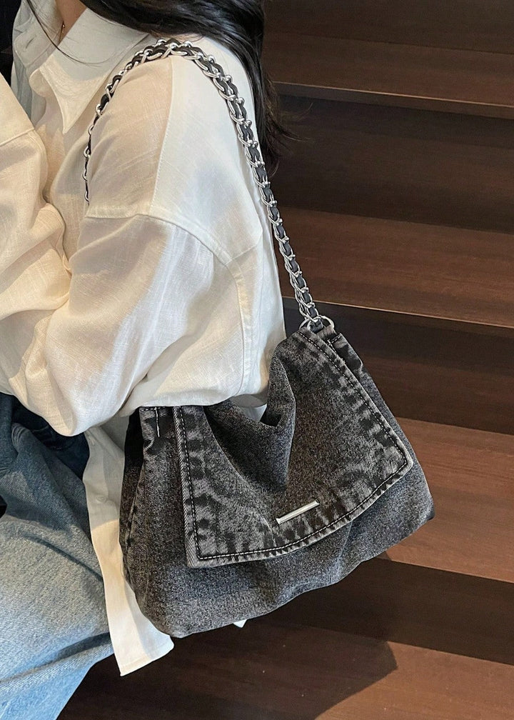 Gesloten dames denim schoudertas met metallic ketting. Trendy spijkerstof accessoire.