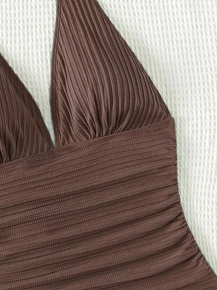 Trendy donkerbruin dames halter badpak. Combineert een diepe V-hals met ribstof voor een chique strandlook.