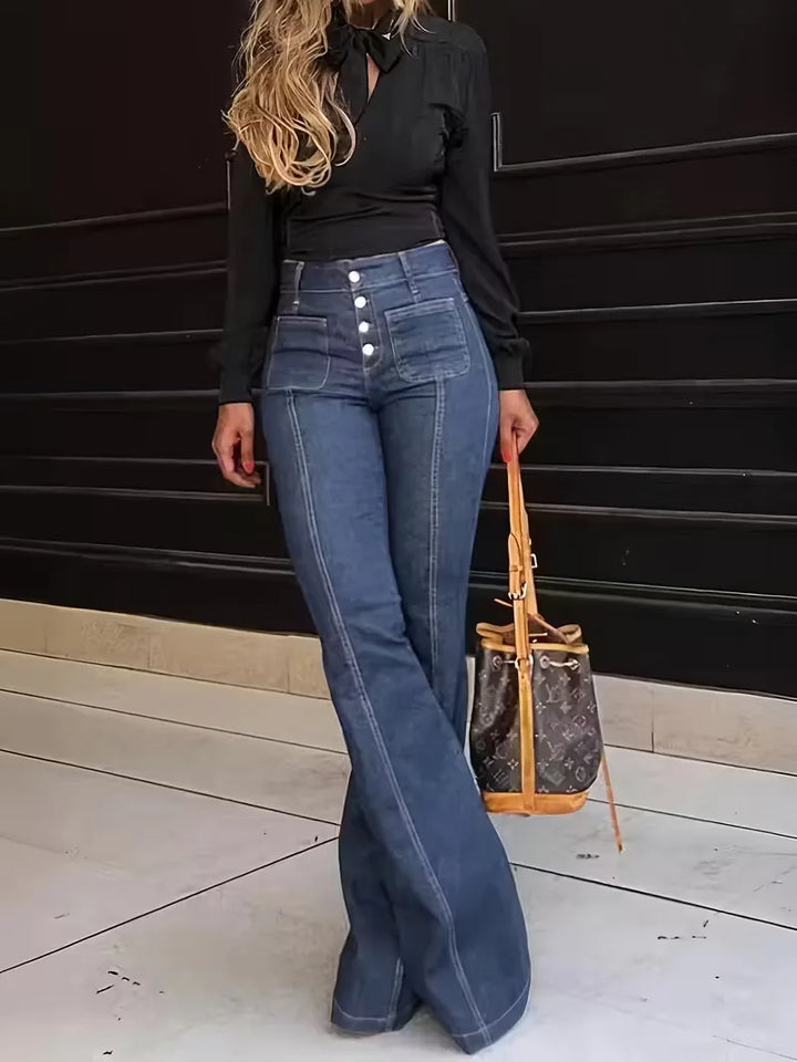 Model draagt donkerblauwe dames flared jeans met hoge taille. Deze trendy wijde pijp jeans combineert stijl en comfort.