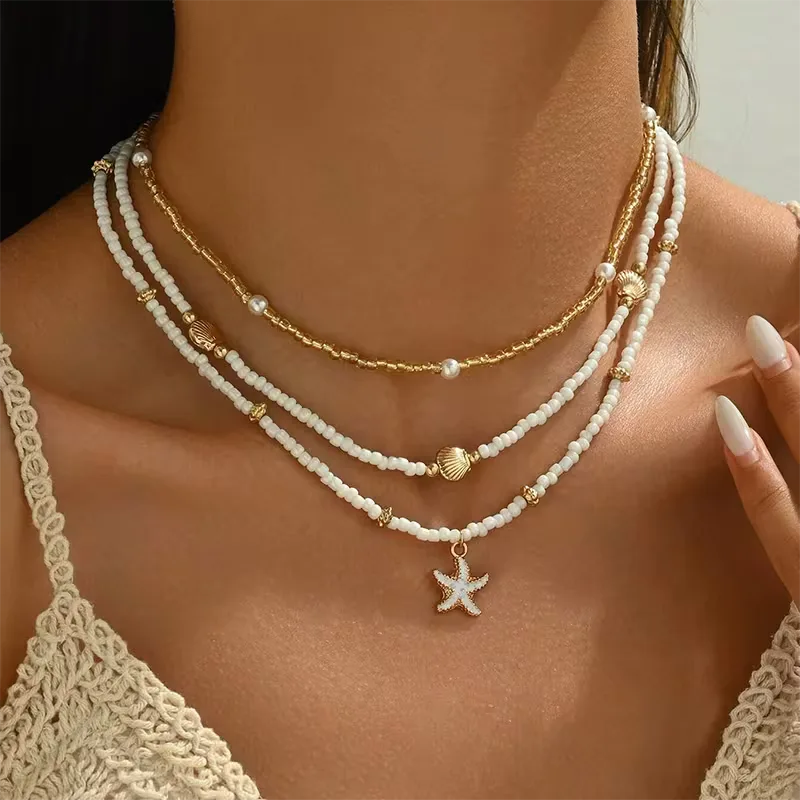Dames gelaagde ketting met schelp, zeester hangers en witte kralen; perfect voor zomerse dagen.
