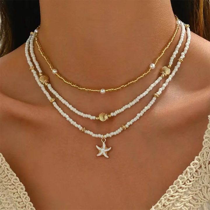 Zomerse damesketting met delicate gouden schelp- en zeesterbedels, ideaal vakantie accessoire.