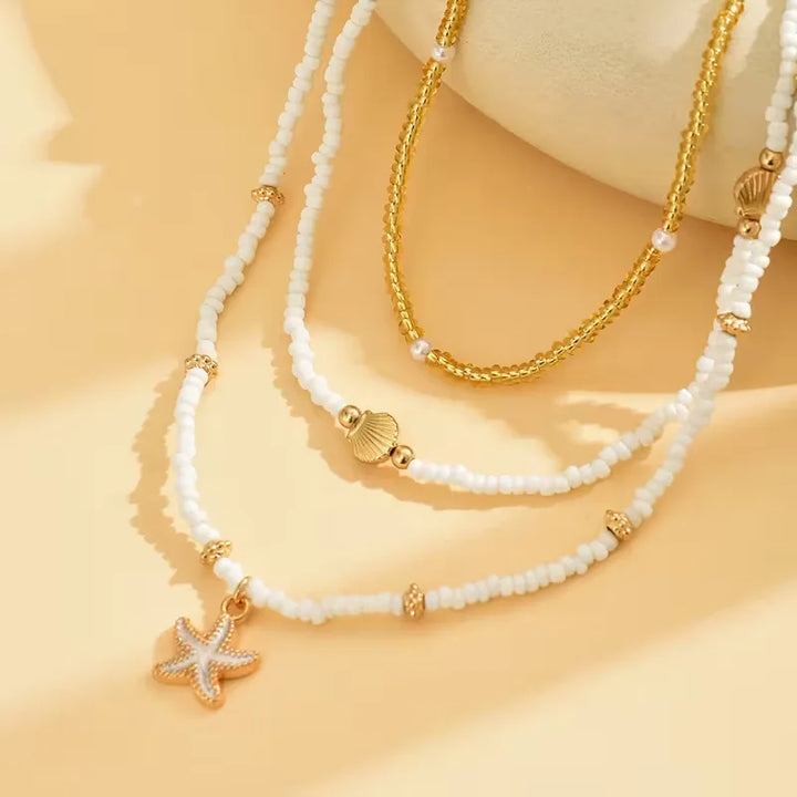 Gouden damesketting met kunstparels, schelp en zeester hangers; minimalistisch en zomers.
