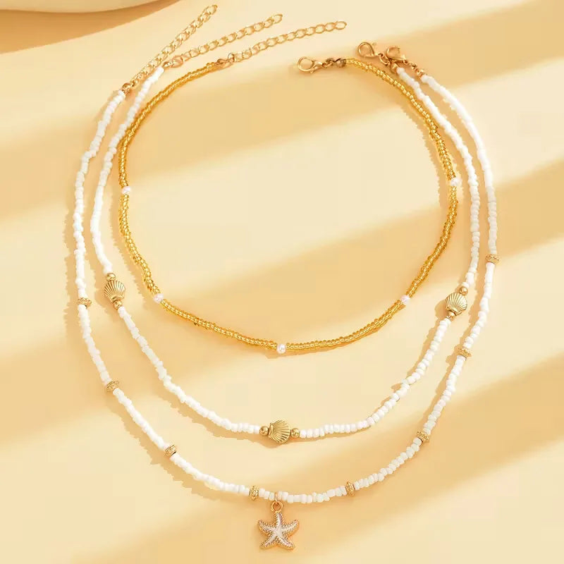 Damesketting met gouden schelp en zeester hangers, perfect voor een zomerse strandlook.