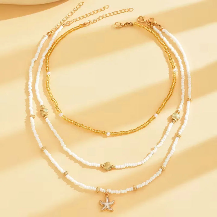 Damesketting met gouden schelp en zeester hangers, perfect voor een zomerse strandlook.