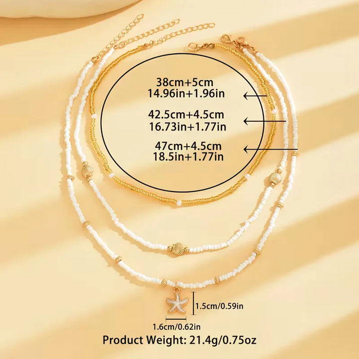 Gelaagde damesketting met schelp, zeester en parels; stijlvol voor de zomer en strand.
