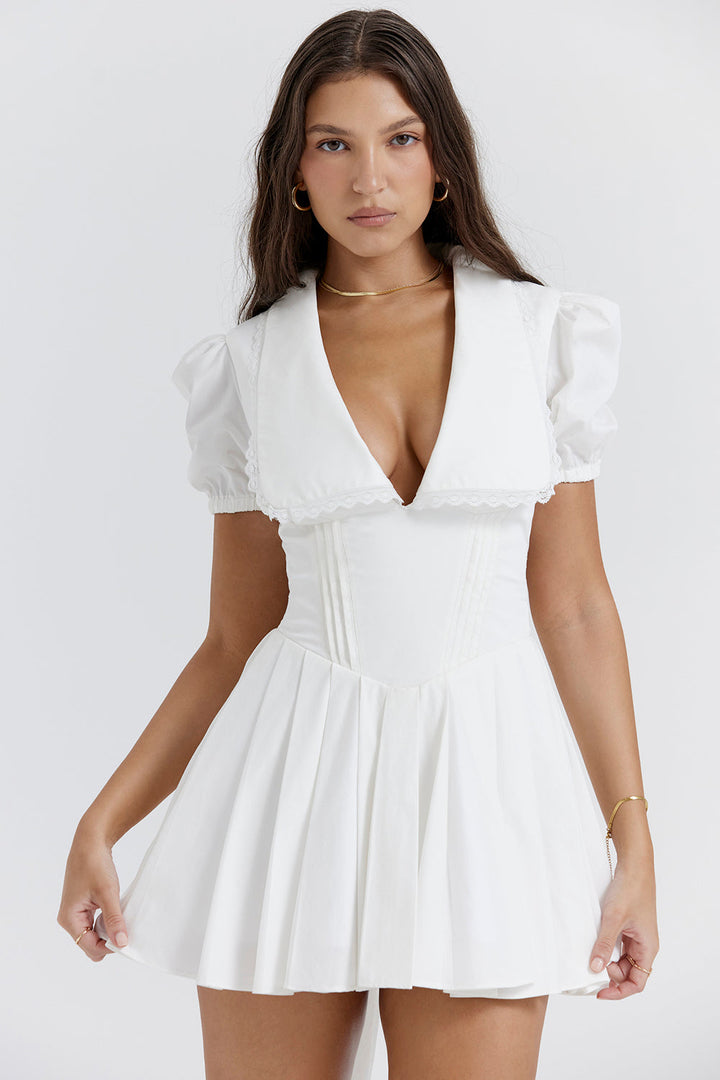 Close-up geplooide stof dames mini-jurk met verfijnde pofmouwen en V-hals. Perfect als casual of feestjurk.