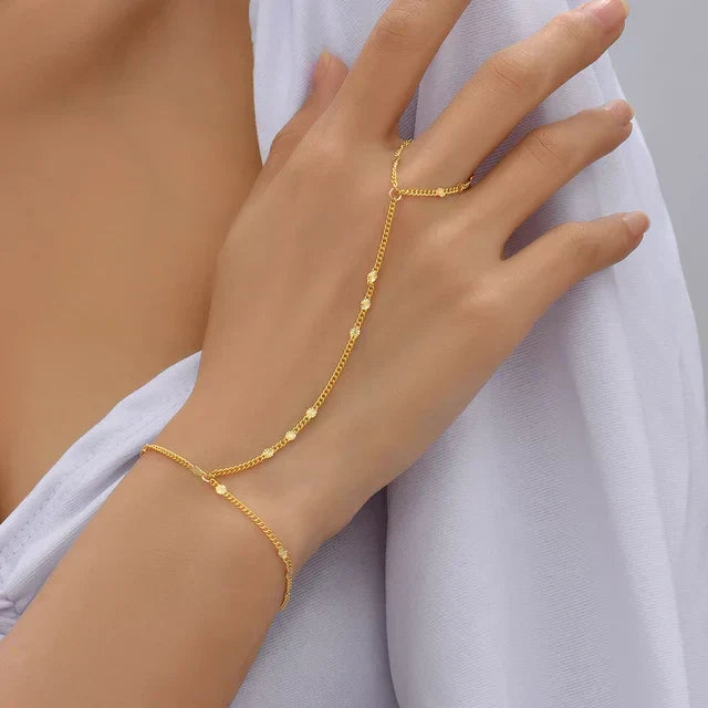 Dameshand met elegante goudkleurige handketting, stijlvol om de pols en hand gedragen.