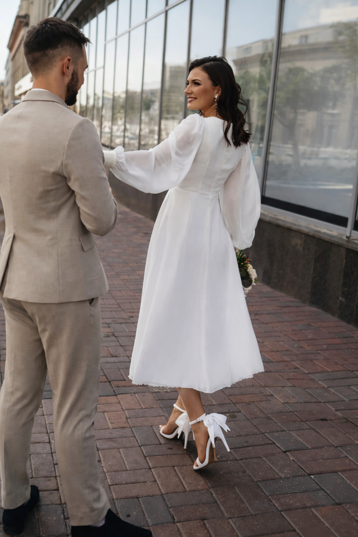 Trendy witte dameskleding jurk met V-hals en elegante pofmouwen. Lange mouwen voor een feestelijke look.