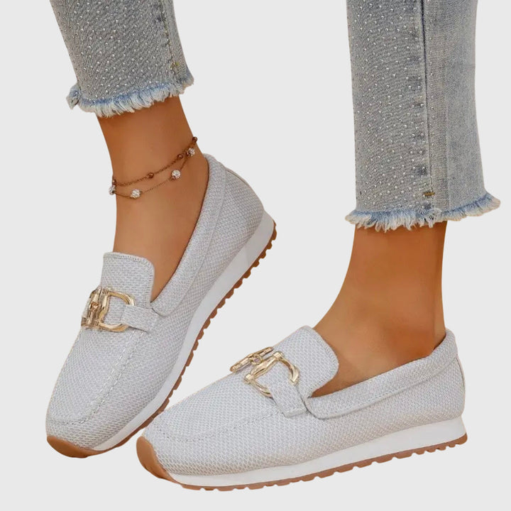 Detailopname van gouden gesp op zwarte dames loafers met trendy plateauzool.