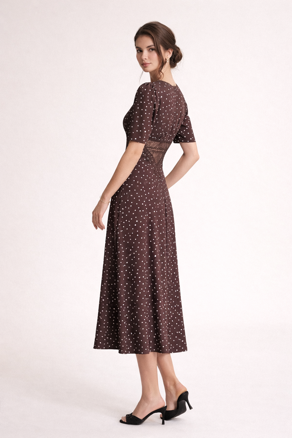 Close-up van de bruine dames midi-jurk, toont de trendy stippenprint en de chique V-hals.