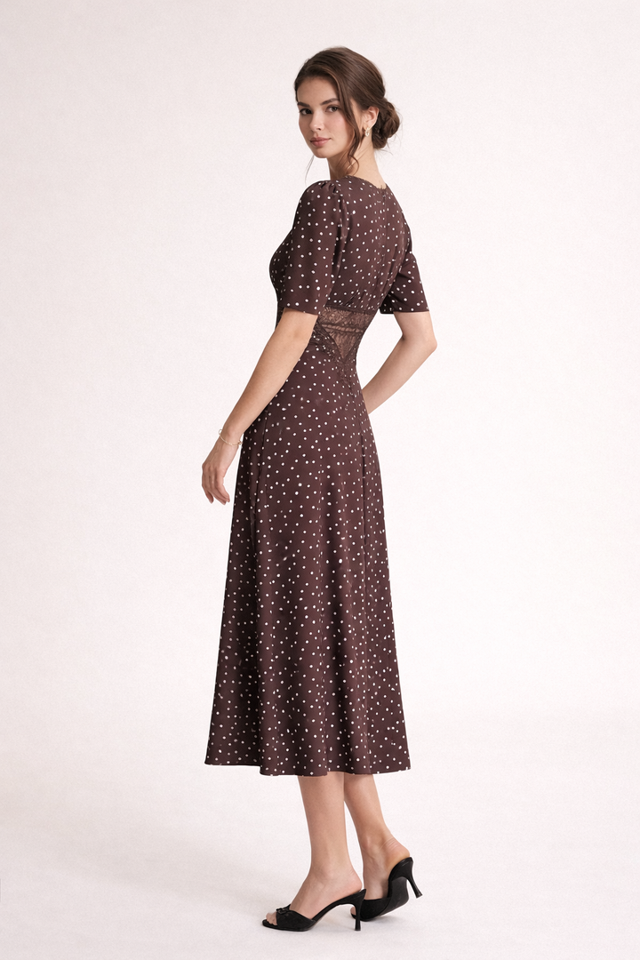 Close-up van de bruine dames midi-jurk, toont de trendy stippenprint en de chique V-hals.