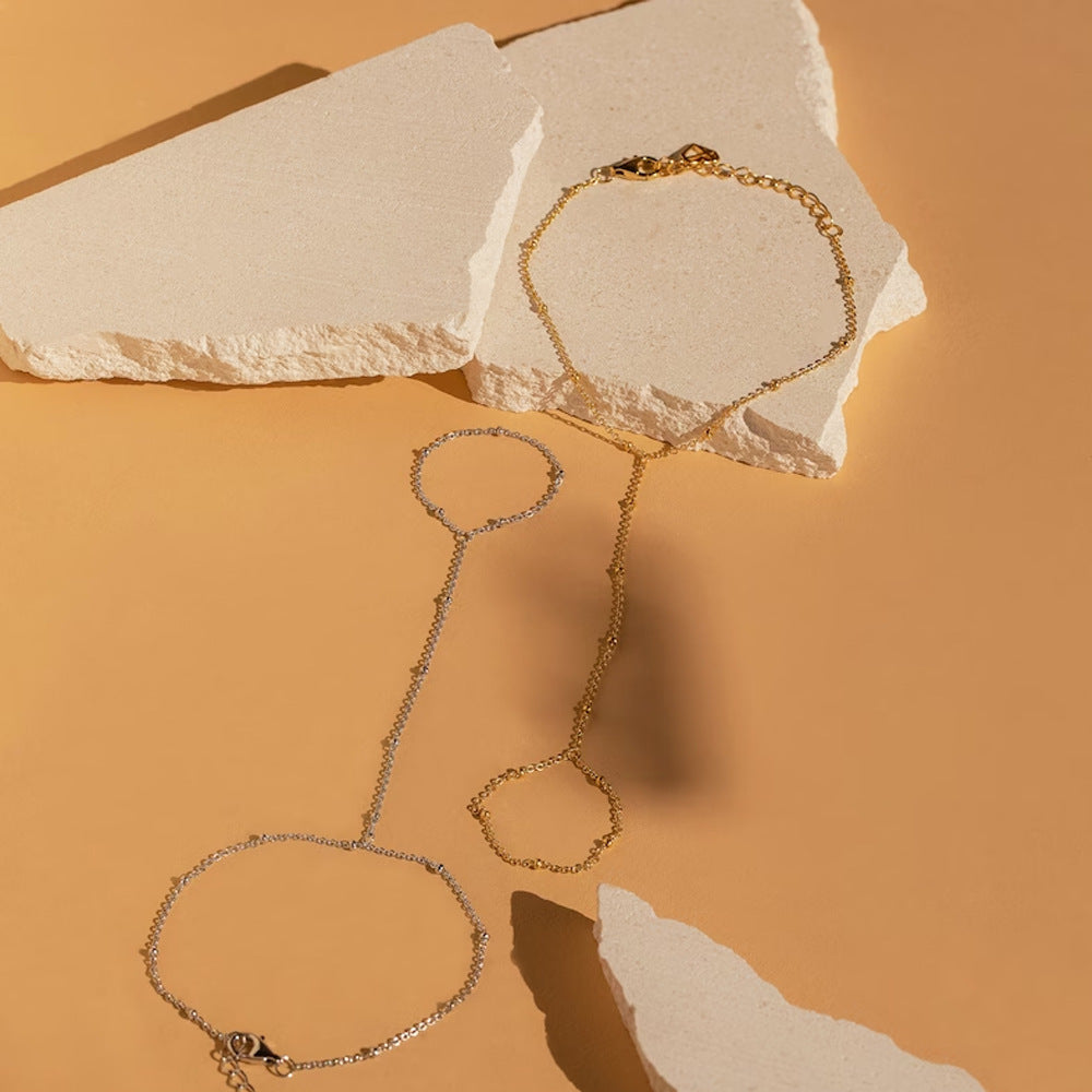 Zilverkleurige minimalistische handketting en ring sieraad voor dames, een moderne mode accessoire.