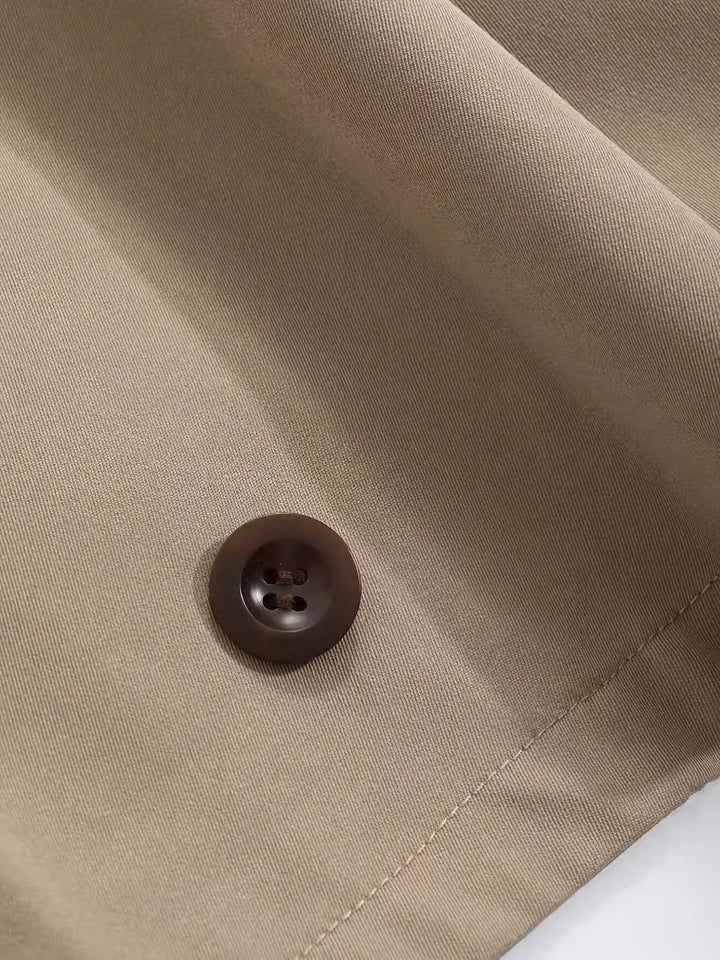 Zijprofiel van een oversized dames trenchcoat, vloeiende lijnen, moderne pasvorm.