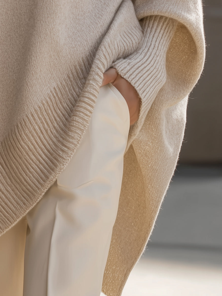 Detailopname van de asymmetrische zoom op een dames poncho-pullover, perfect voor de koudere herfstdagen.