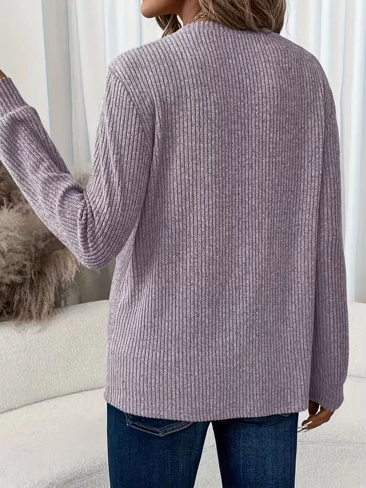 Detailopname van de zachte ribbelstof van deze gebreide damestrui.