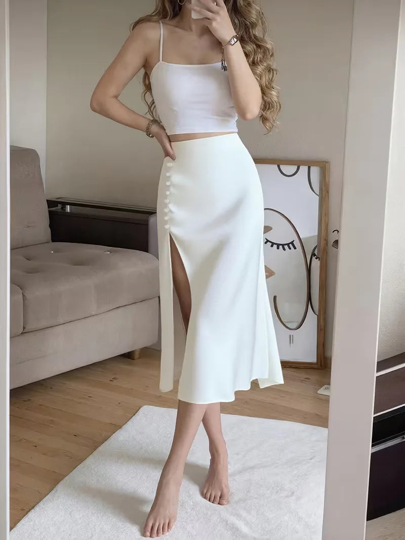 Donkerblauwe satijnen midi rok met hoge split en knoopdetails, elegant voor najaar.