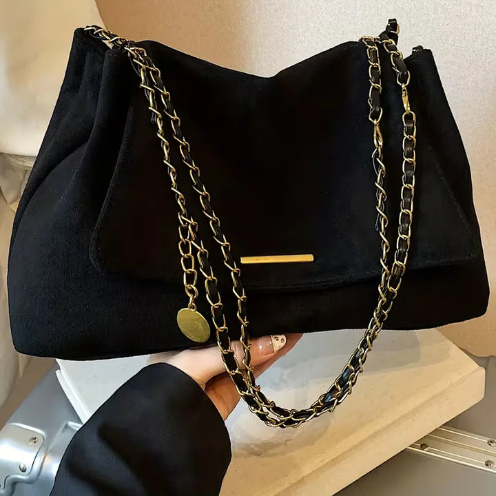 Moderne dames schoudertas van faux suède met kettingband. Stijlvol en compact, deze tas maakt elke casual chic look compleet.
