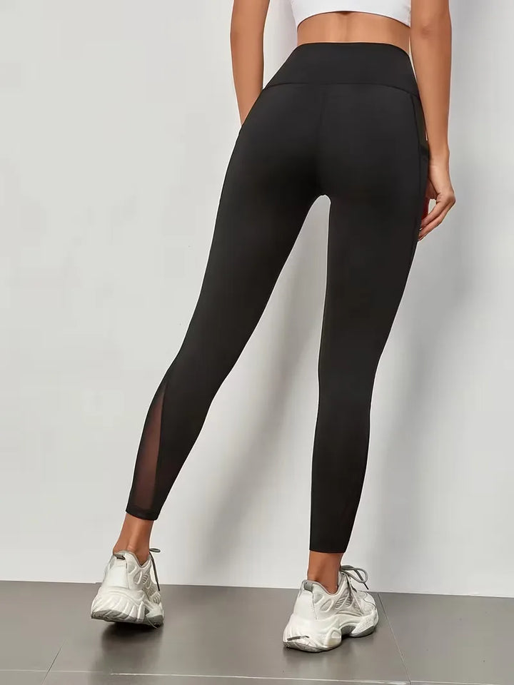 Zwarte dameslegging met hoge taille, ademende mesh panelen en praktische zijzakken voor workouts.