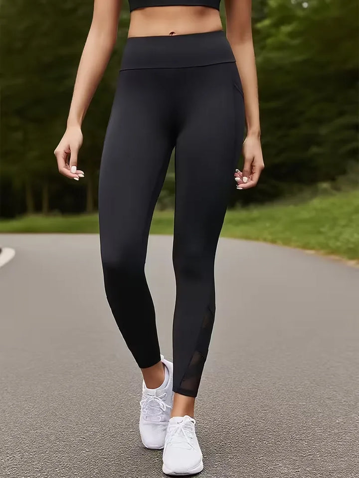Zwarte dames sportlegging met transparante mesh inzetstukken. Ergonomisch design voor fitness en sport. Hoge taille.