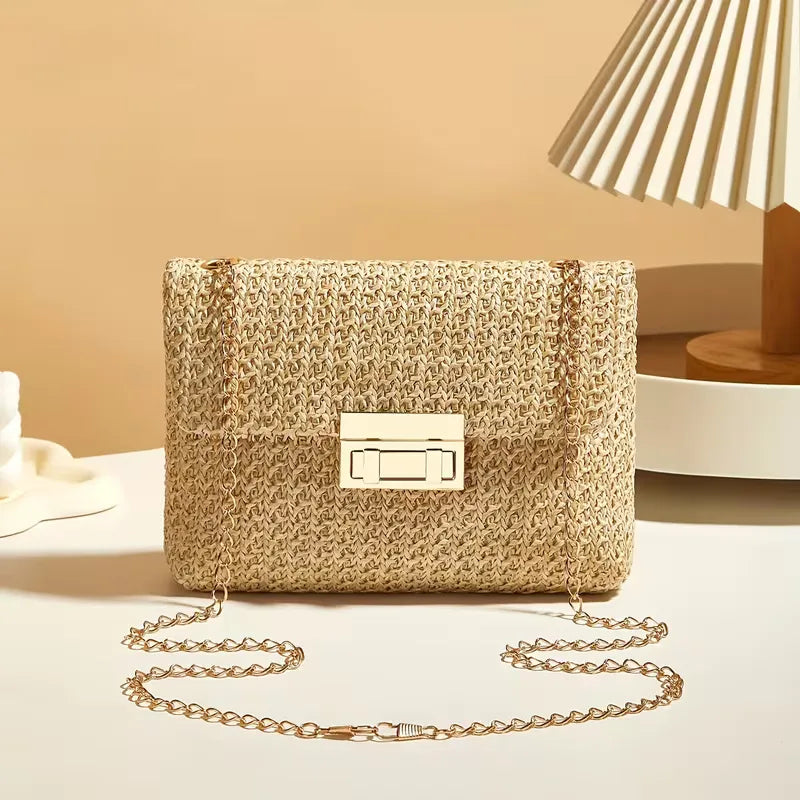 Compacte dames schoudertas van stro met gouden accenten, geschikt als handtas voor de zomer.