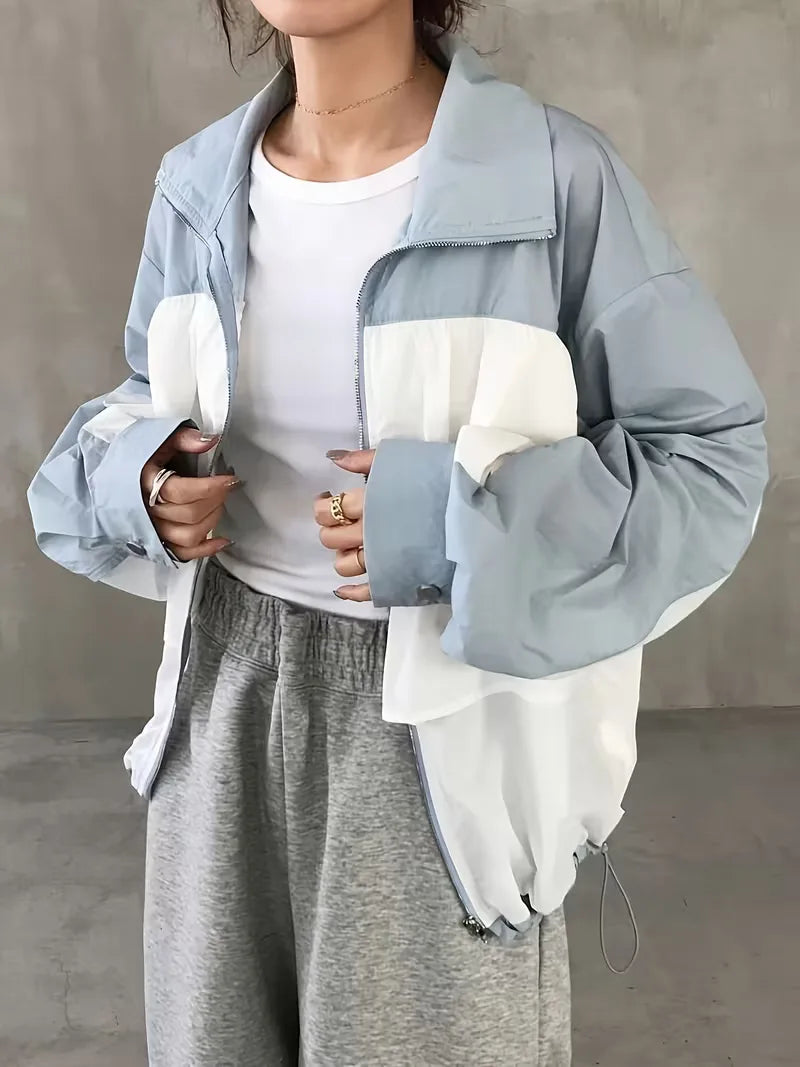 Trendy colorblock dames trackjacket met capuchon in frisse wit-lichtblauwe tinten, moderne casual streetwear look.