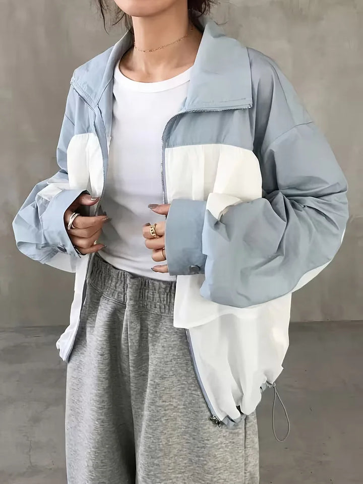 Trendy colorblock dames trackjacket met capuchon in frisse wit-lichtblauwe tinten, moderne casual streetwear look.