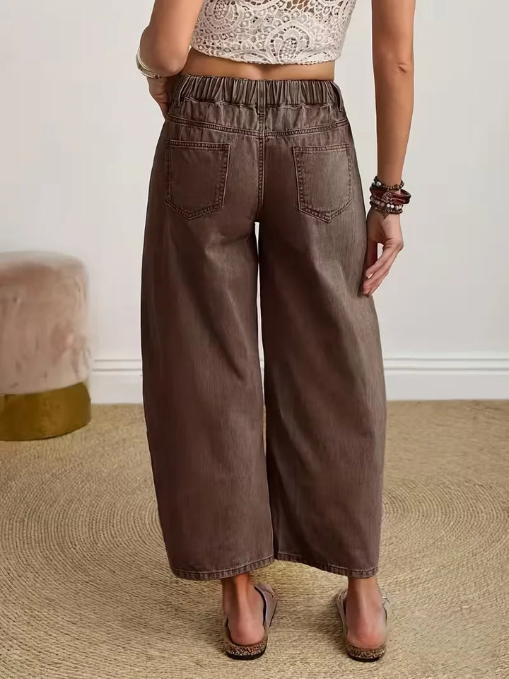 Gedetailleerde foto van de wijde pijpen en knoopsluiting van deze casual damesbroek in koffiekleur.