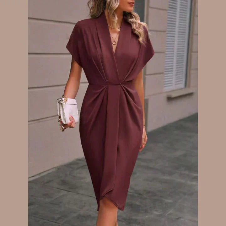 Vrouw draagt een elegante, korte dames wikkeljurk. Flatterend en modieus, perfect als zomerjurk voor haar.