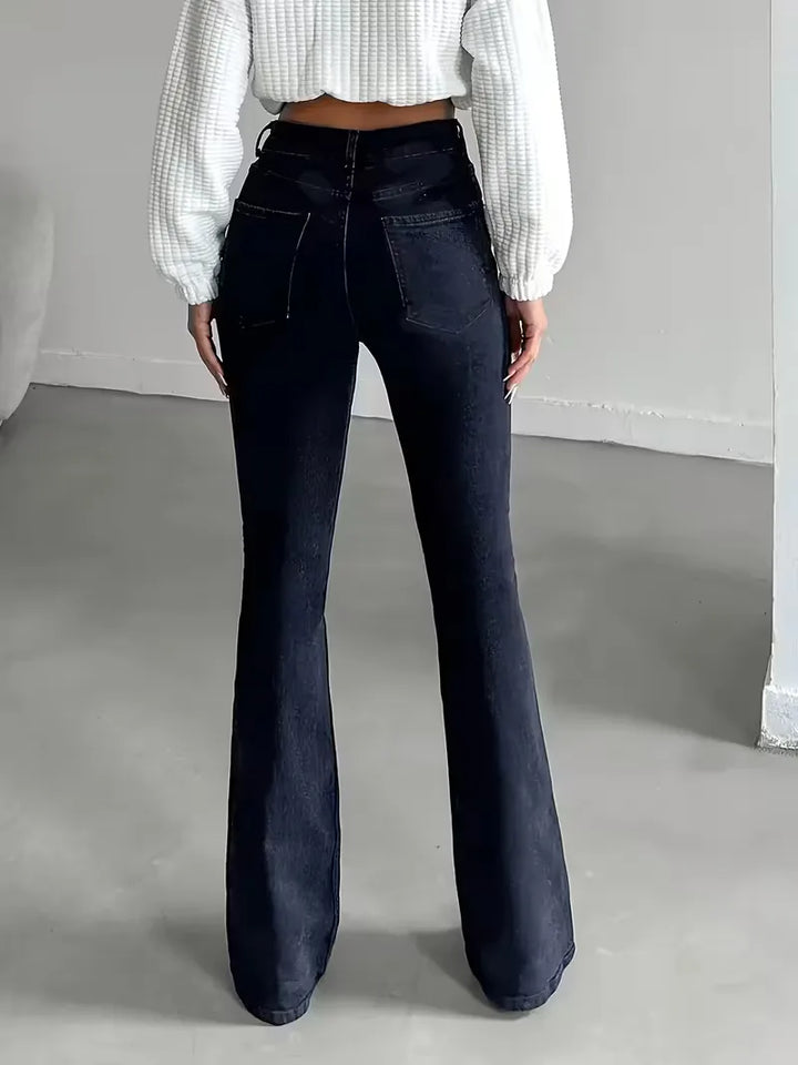 Model draagt comfortabele donkerblauwe dames flared jeans met hoge taille en wijde pijpen, lente/zomer stijl.