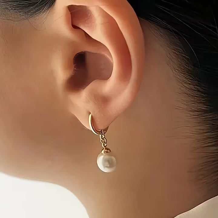 Detailopname van elegante damesketting met glanzende faux parels en de bijpassende goudkleurige oorbellen.
