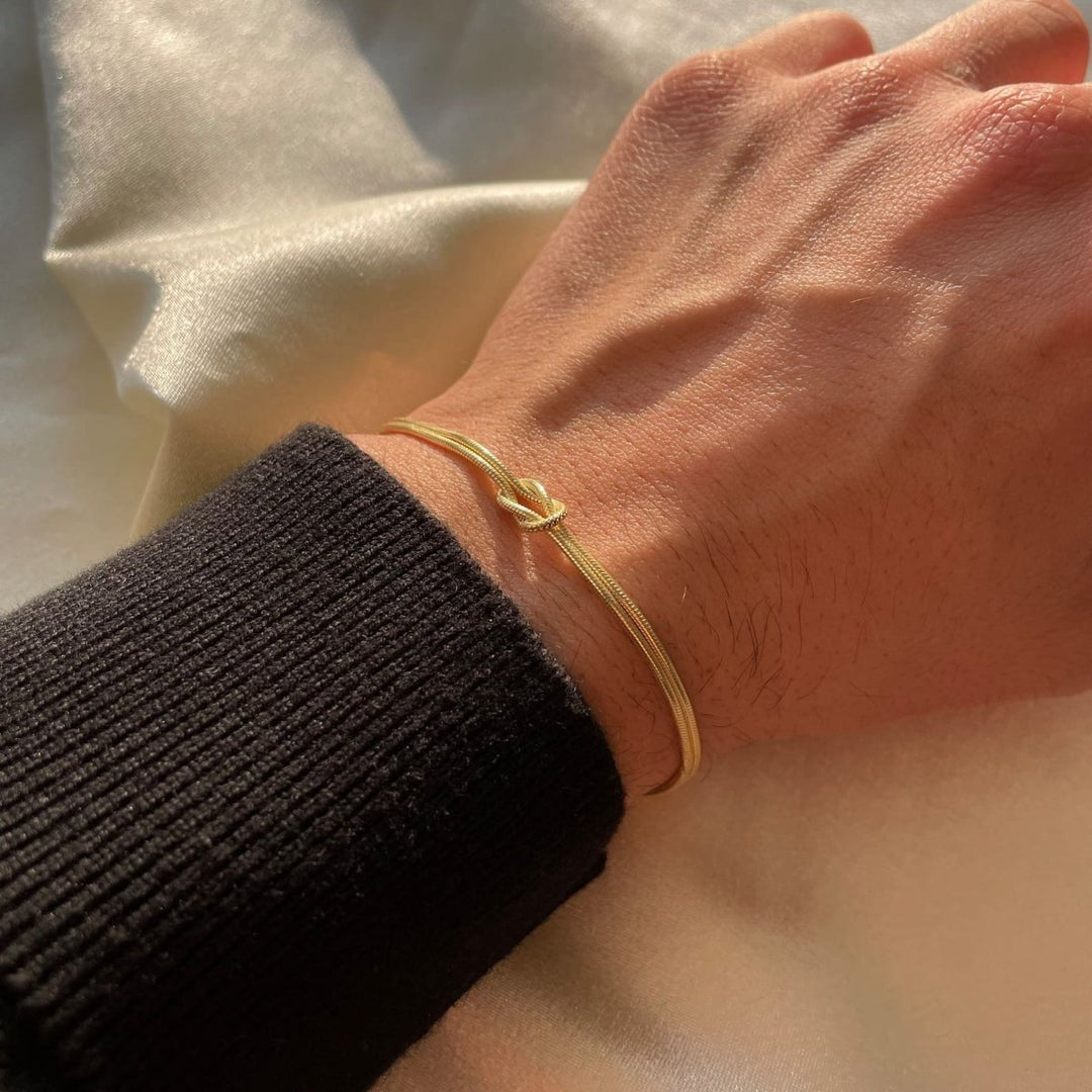 Damesarmband met liefdesknoop, minimalistisch en elegant, gedragen aan de pols.