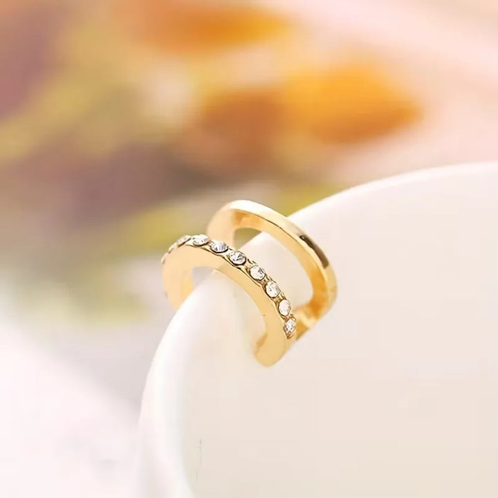 Gouden clip-on oorbel voor dames met uniek handdesign en sprankelende stenen, ideaal voor een stijlvolle outfit.