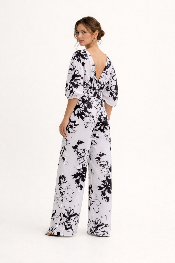Witte dames jumpsuit met levendige bloemenprint en wijde pijpen, ideaal voor een zomerse feestoutfit.