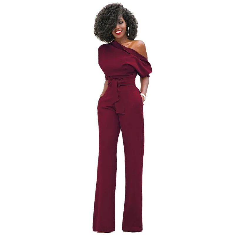 Flatterende asymmetrische dames jumpsuit met open schouder en decoratieve strikband. Perfect voor feestjes.