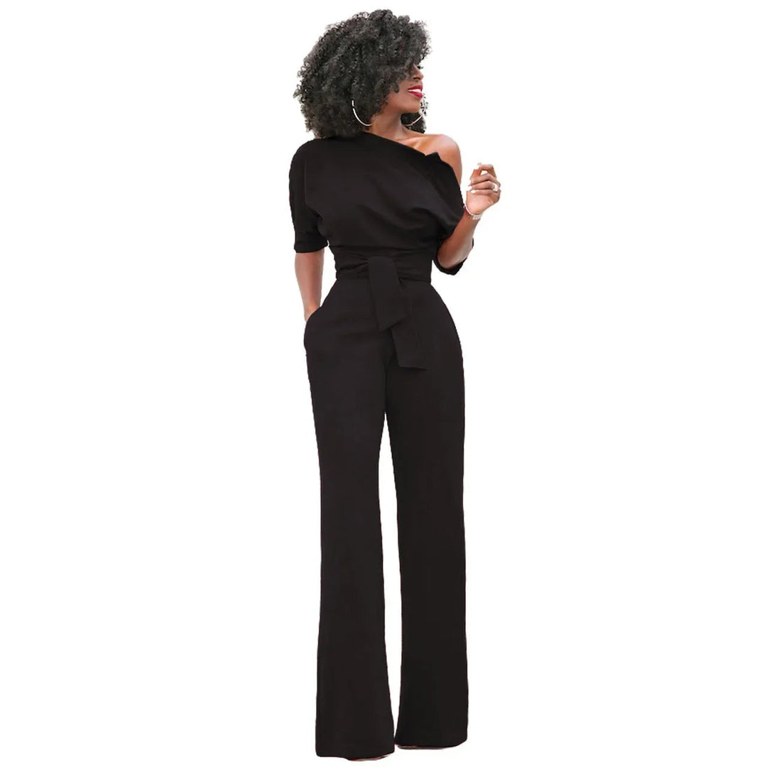Model draagt elegante dames jumpsuit met open schouder, strikband en wijde pijpen. Ideaal voor avondkleding.