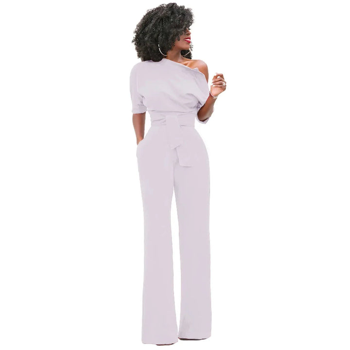 Vloeiende dames jumpsuit met open schouder, strikband en wijde pijpen. Geschikt als feest- of zomerjumpsuit.