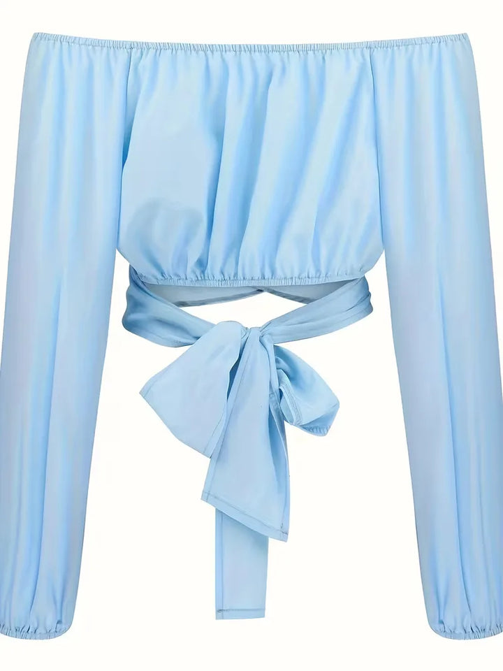 Lichtblauwe off-shoulder damesblouse met lange mouwen en strikdetails, modieus voor de zomer.